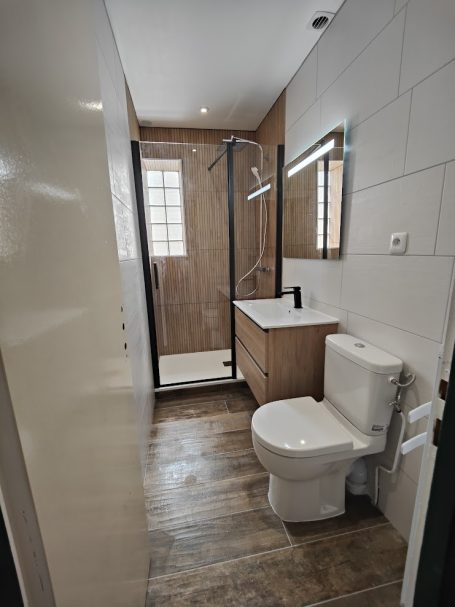 Salle de bain moderne avec douche, lavabo et toilette, décor en bois et carrelage.